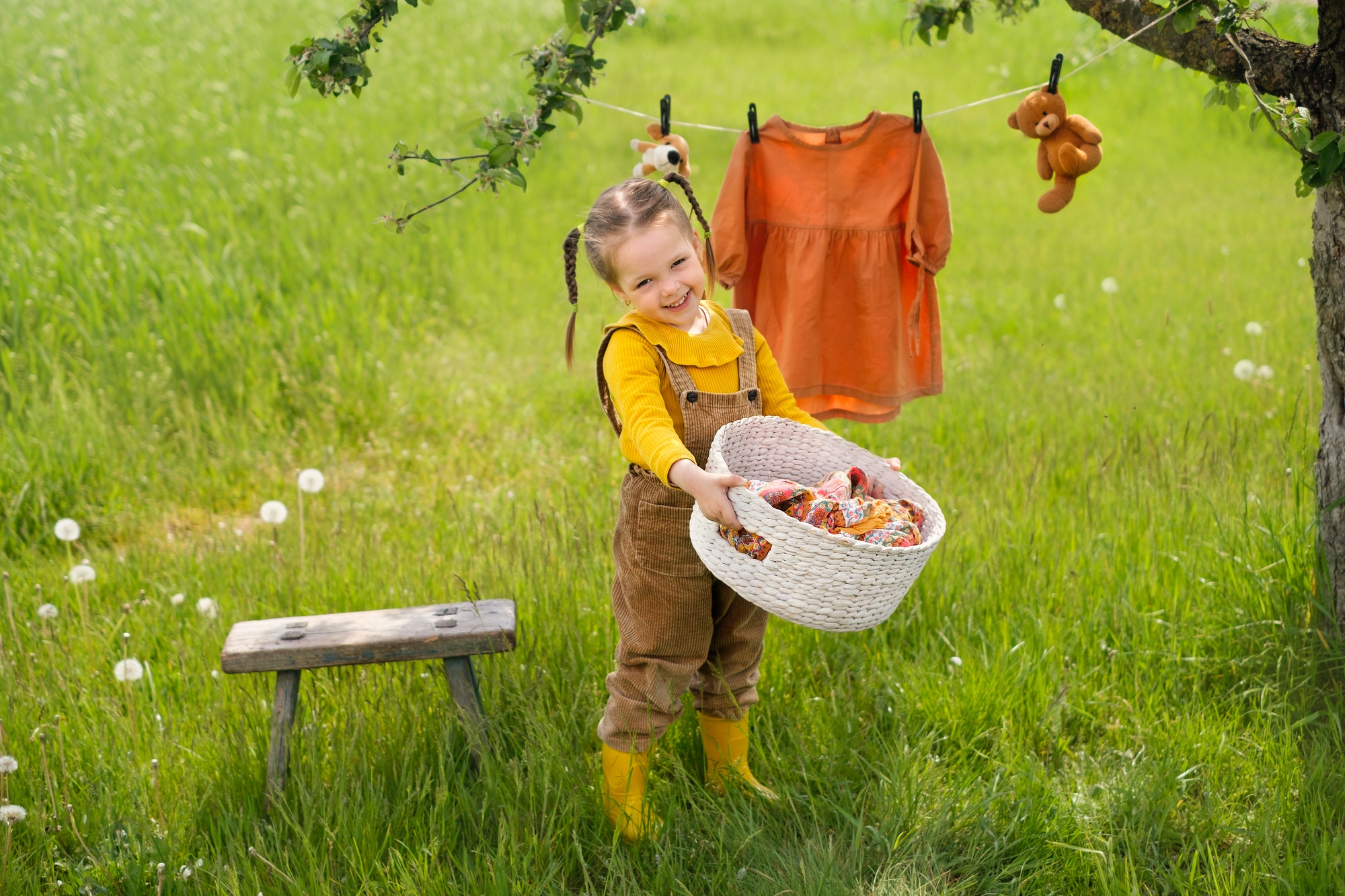 Smiling girl is standing with basket of clean wet laundry